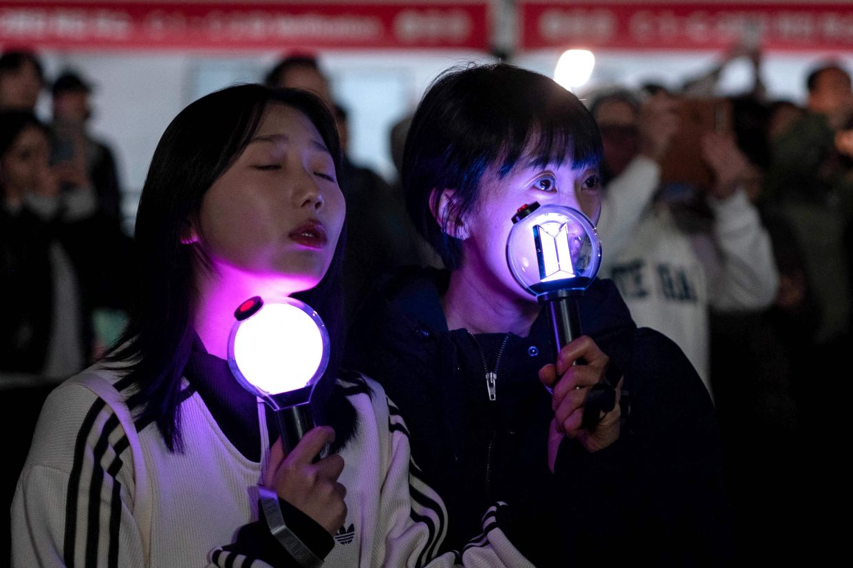 Fans react as they watch the comeback concert of K-pop boy group BTS on a screen at the venue in Seoul on Saturday, March 21, 2026. South Korean megastars BTS reunited on March 21 for their first show in nearly four years, blowing away enormous crowds in Seoul for a K-pop extravaganza livestreamed to millions more worldwide. -- Photo by Roland DE COURSON / AFP