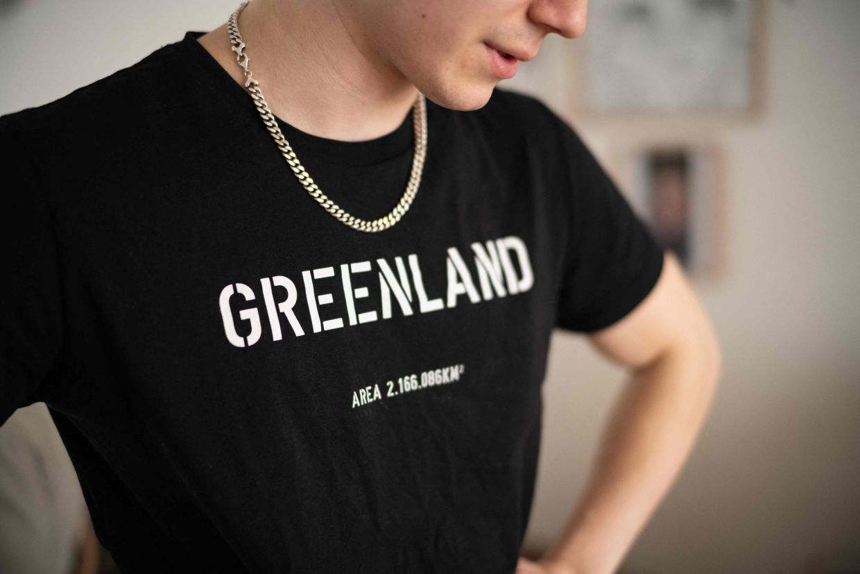 Kian, a 19-year-old boxer who lost his mother, stands in his living room wearing a Greenland T-shirt, in Nuuk, Greenland, on March 8, 2026. Greenland has one of the highest suicide rates in the world, especially among teenagers and young adults. In the capital, many turn to boxing as a way to channel their pain.