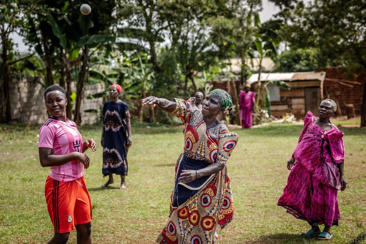 An elderly woman delivers the ball during a cricket and physical training session in Jinja.