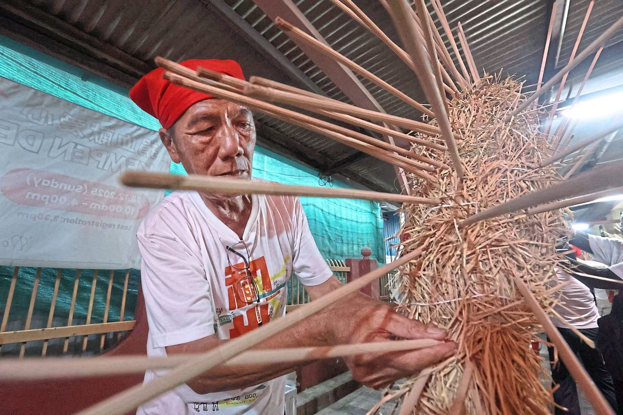 A volunteer inserting joss sticks into the straw dragon during preparations for the procession.