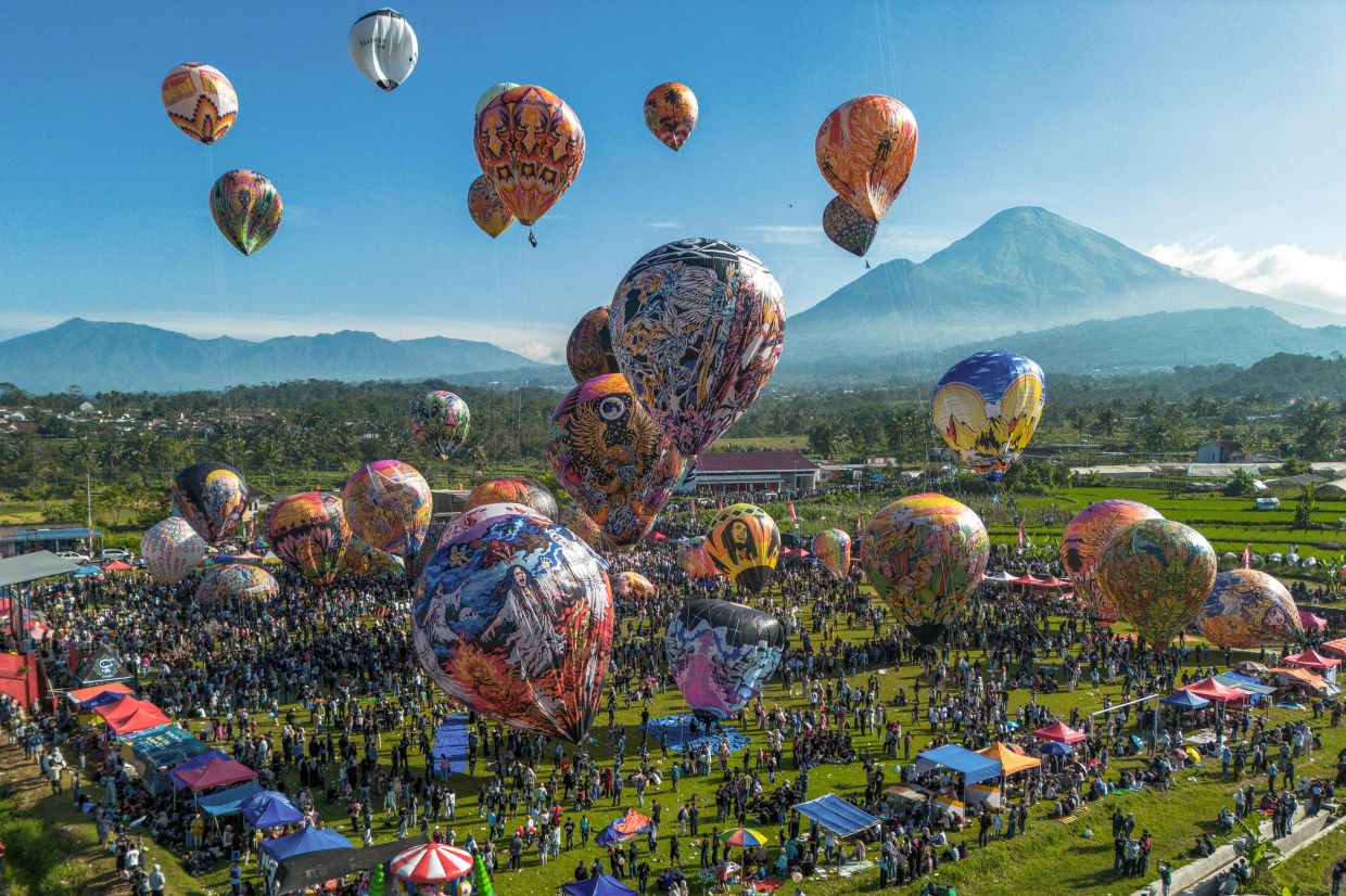 An aerial view shows hot air balloons decorated with traditional motifs before their launch during the annual hot air balloon festival held to celebrate Eid al-Fitr, which marks the end of the Islamic holy fasting month of Ramadan, at Semayu village in Wonosobo, Central Java on Monday, March 23, 2026. -- Photo by DEVI RAHMAN / AFP