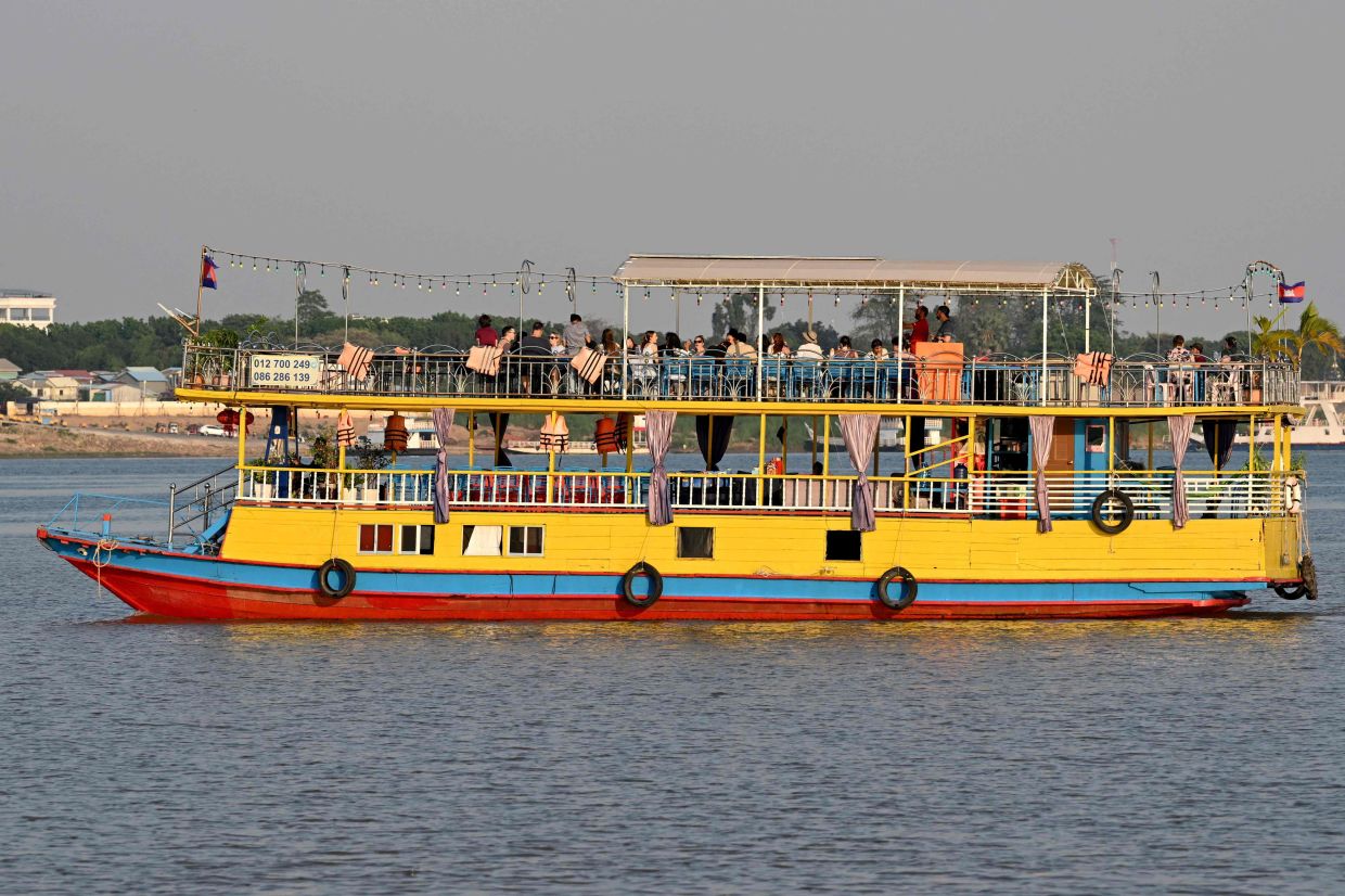 Tourists are enjoying the sights on a tourist boat as they travel along the Mekong River in Phnom Penh. - Photo by TANG CHHIN Sothy / AFP