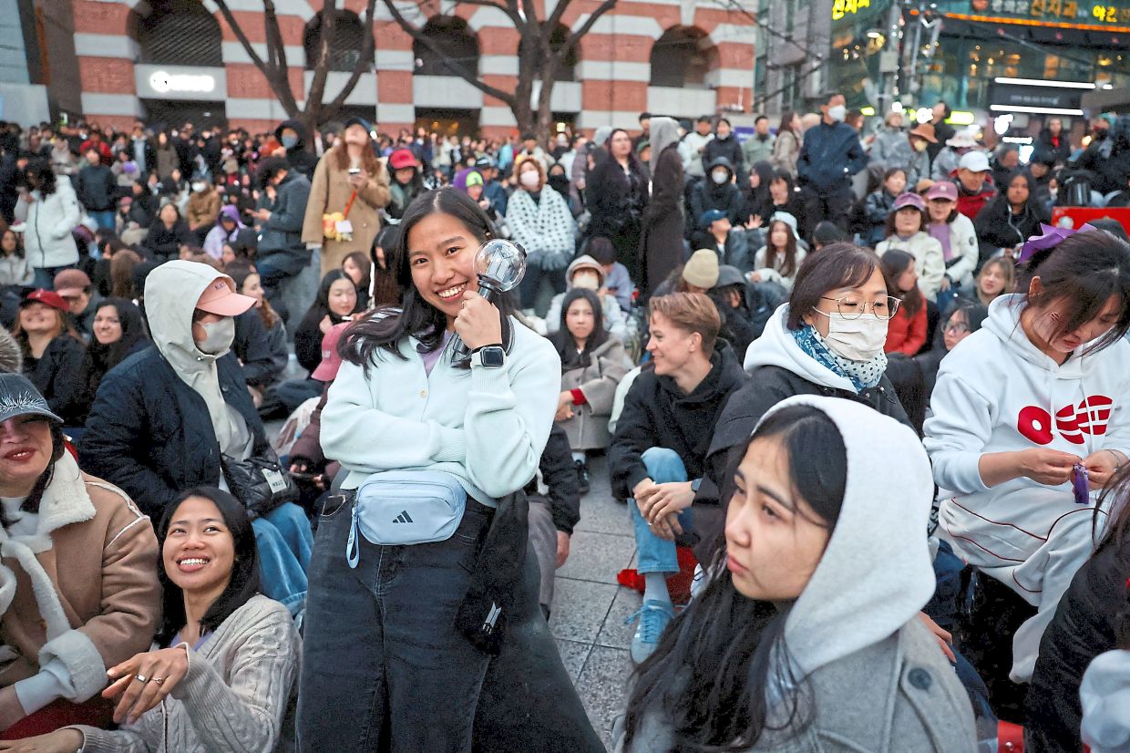 5. An ARMY, who was unable to secure a ticket to the free concert, clutching a BTS light stick while waiting outside the concert area. — Reuters
