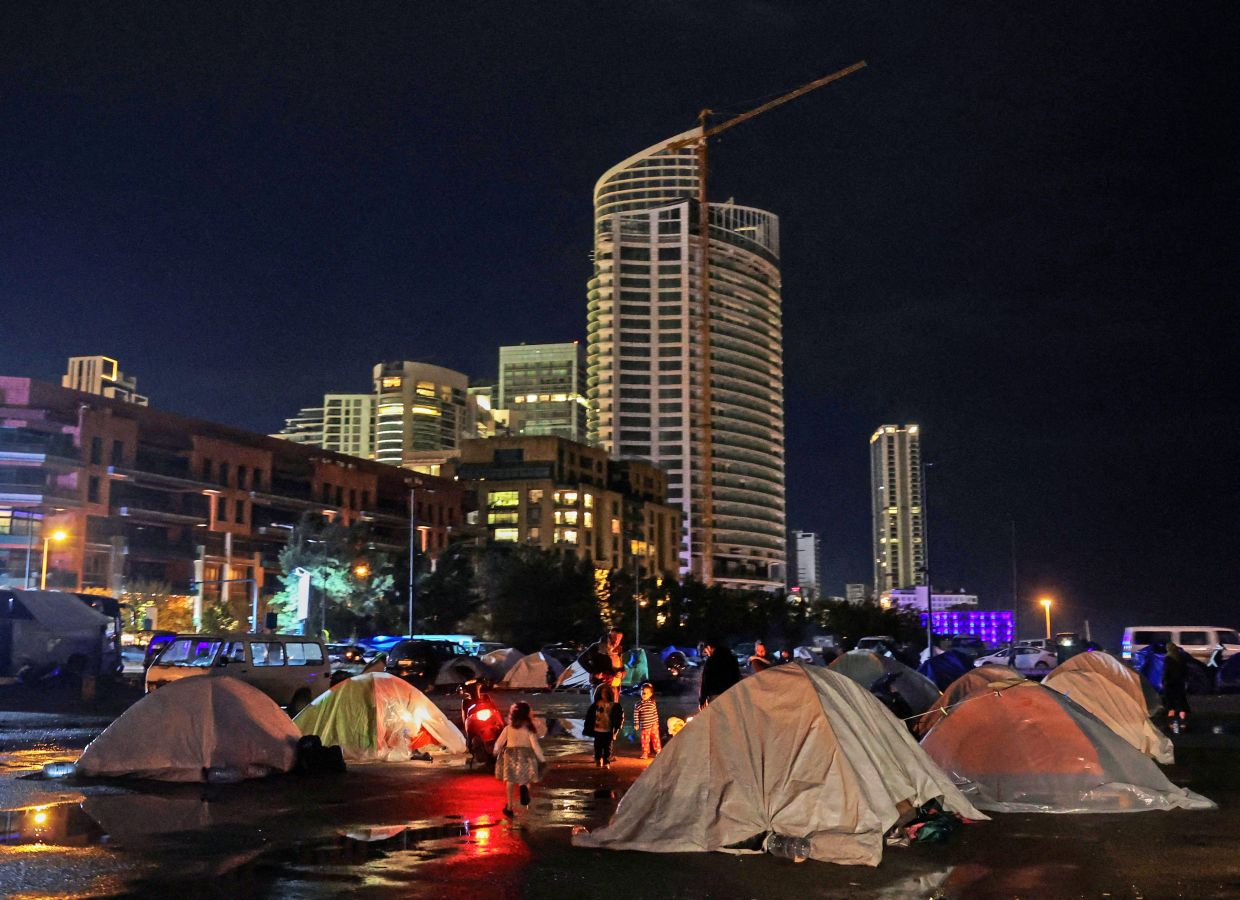 7. Displaced residents walking among tents in a temporary encampment in Beirut, Lebanon. — Reuters