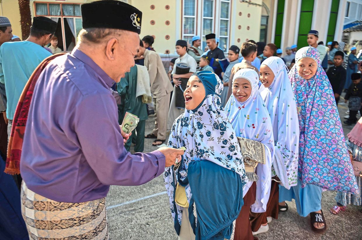 8. A man distributing money to children at a mosque in Narathiwat, Thailand. — AFP