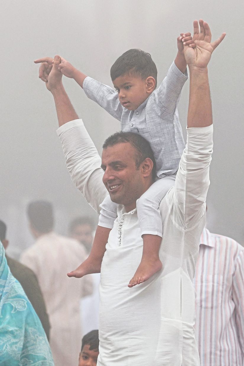 1. A man carrying a child on his shoulders after Aidilfitri prayers at Jama Masjid in the old quarters of New Delhi, India. — Reuters