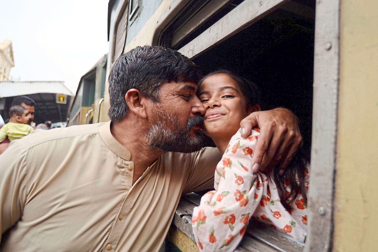 3. A man embracing his child as she boards a train to return to her hometown ahead of Aidilfitri in Karachi, Pakistan. — Xinhua