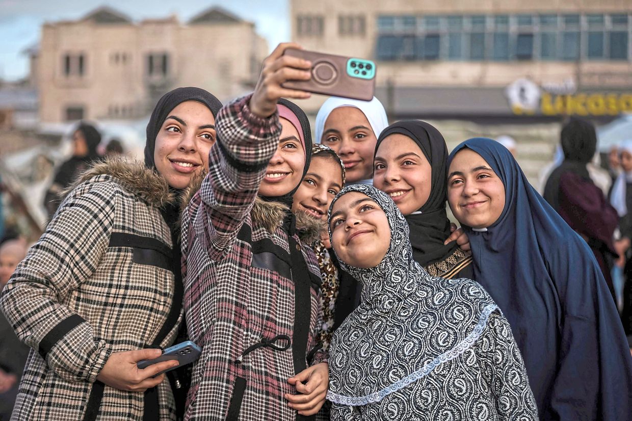 2. Palestinian girls posing for a selfie as they gather for Aidilfitri prayers at Al-Saraya Square in Gaza City. — AFP