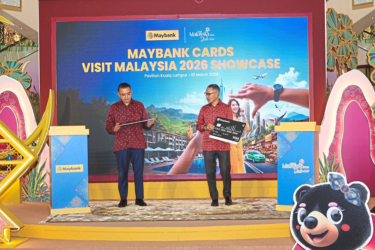 Mohd Amirul Rizal (left) and Syed Ahmad Taufik swiping the mock Maybank credit cards during the launch.