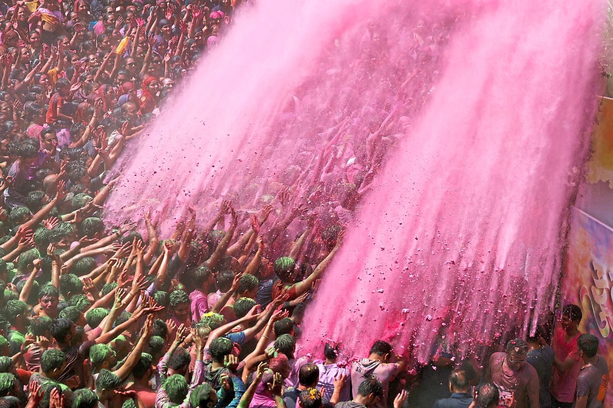 2. Hindu devotees are coated in vibrant powder within a temple complex during Holi festivities in Ahmedabad in India. — Reuters