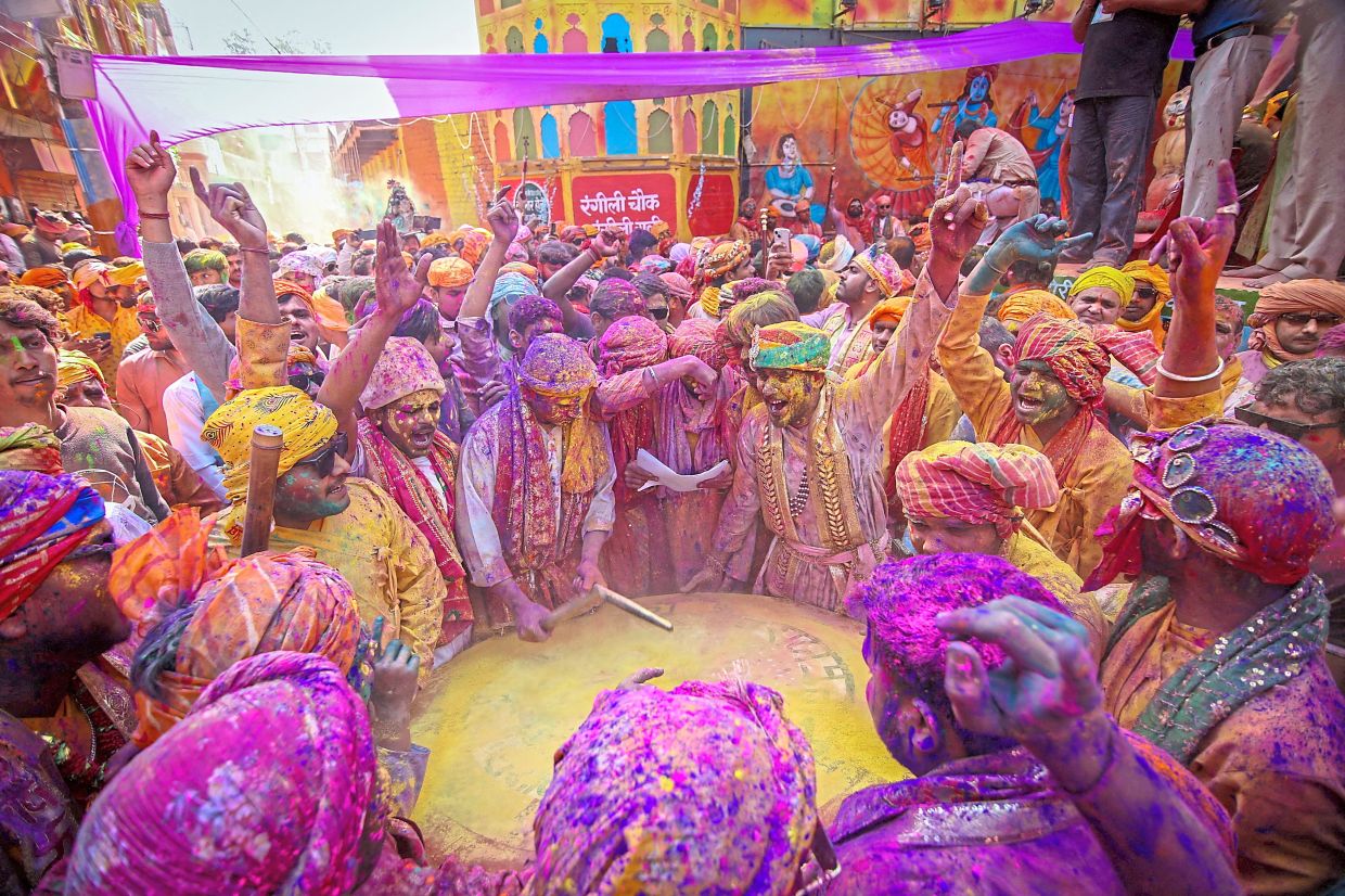 6. Men coated in bright hues hurling coloured powder at one another during Lathmar Holi celebrations in Barsana, Uttar Pradesh. — Reuters