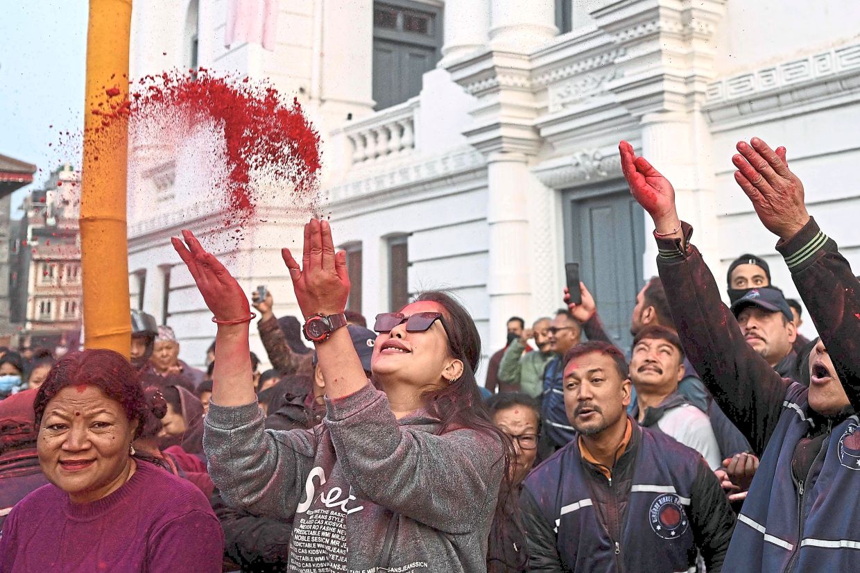 8. Devotees tossing coloured powder toward a sacred bamboo pole, known as the ‘Chir’, adorned with cloth strips symbolising good luck at Basantapur Durbar Square in Kathmandu, Nepal. — AFP
