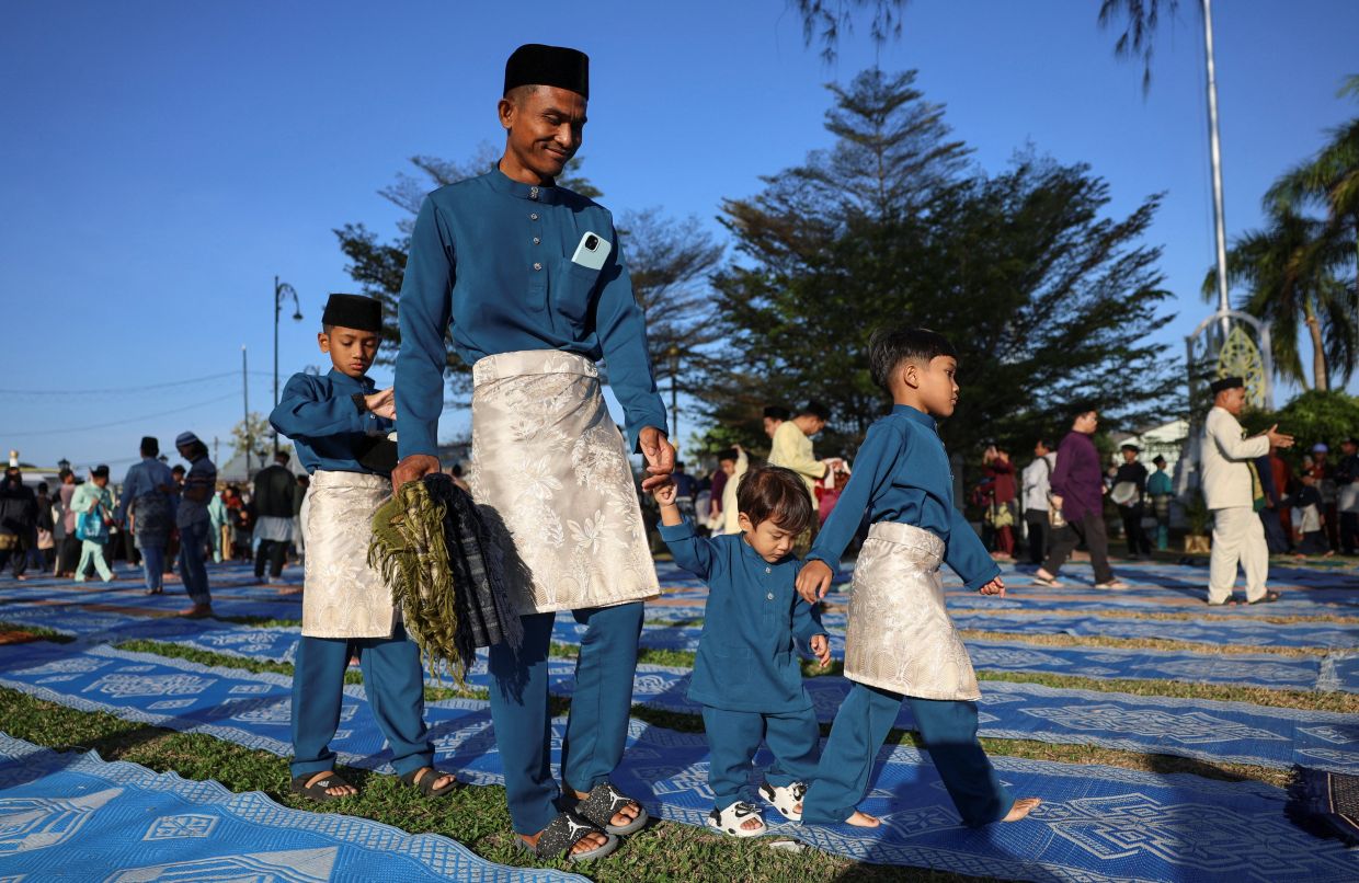 3. A father with his sons attending Aidilfitri prayers in Arau, Perlis, marking the end of the holy month of Ramadan.. — Reuters