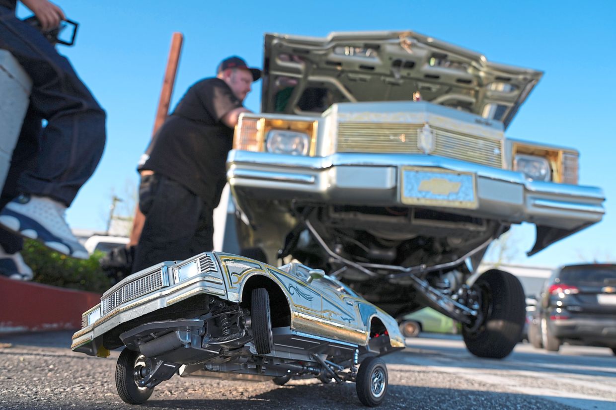 A toy lowrider sits beneath a real one at the 6th Annual Lady Lowrider Cruise Night in Pasadena on March 8, celebrating International Women’s Day.