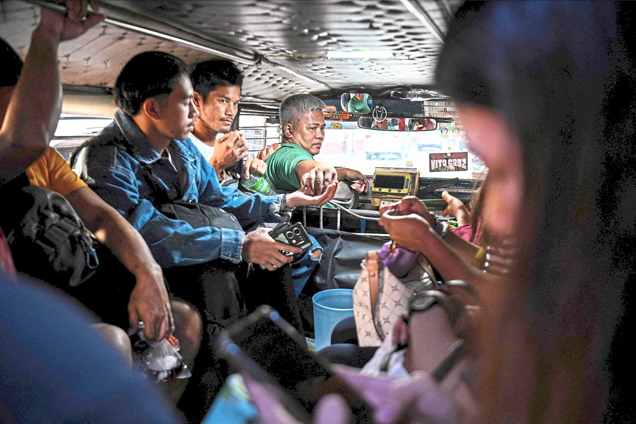 Expensive trip: Helera refuelling his jeepney and (below) collecting fares from passengers while plying his route in Manila. — AFP