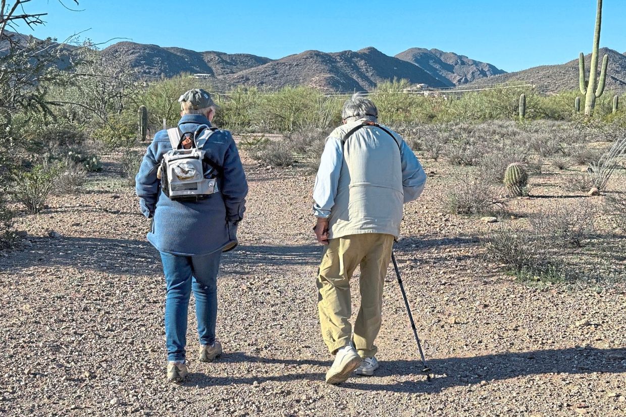 OBara (left) wearing an oxygen pack for her COPD, and birding enthusiast Rhea Guertin walk down a smooth dirt path during an accessible outing.