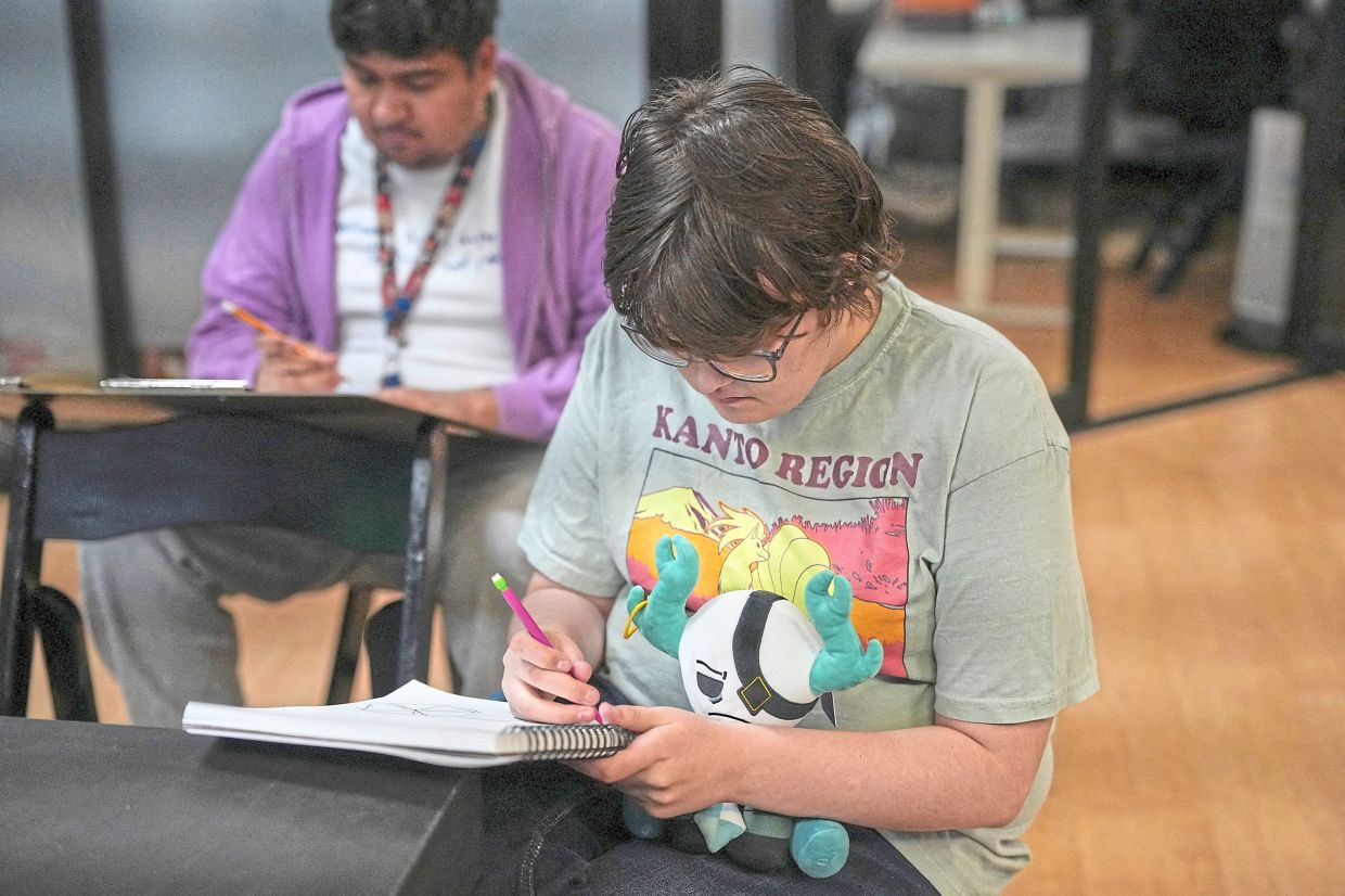 A student works with a stuffed animal on his lap at the studio. 