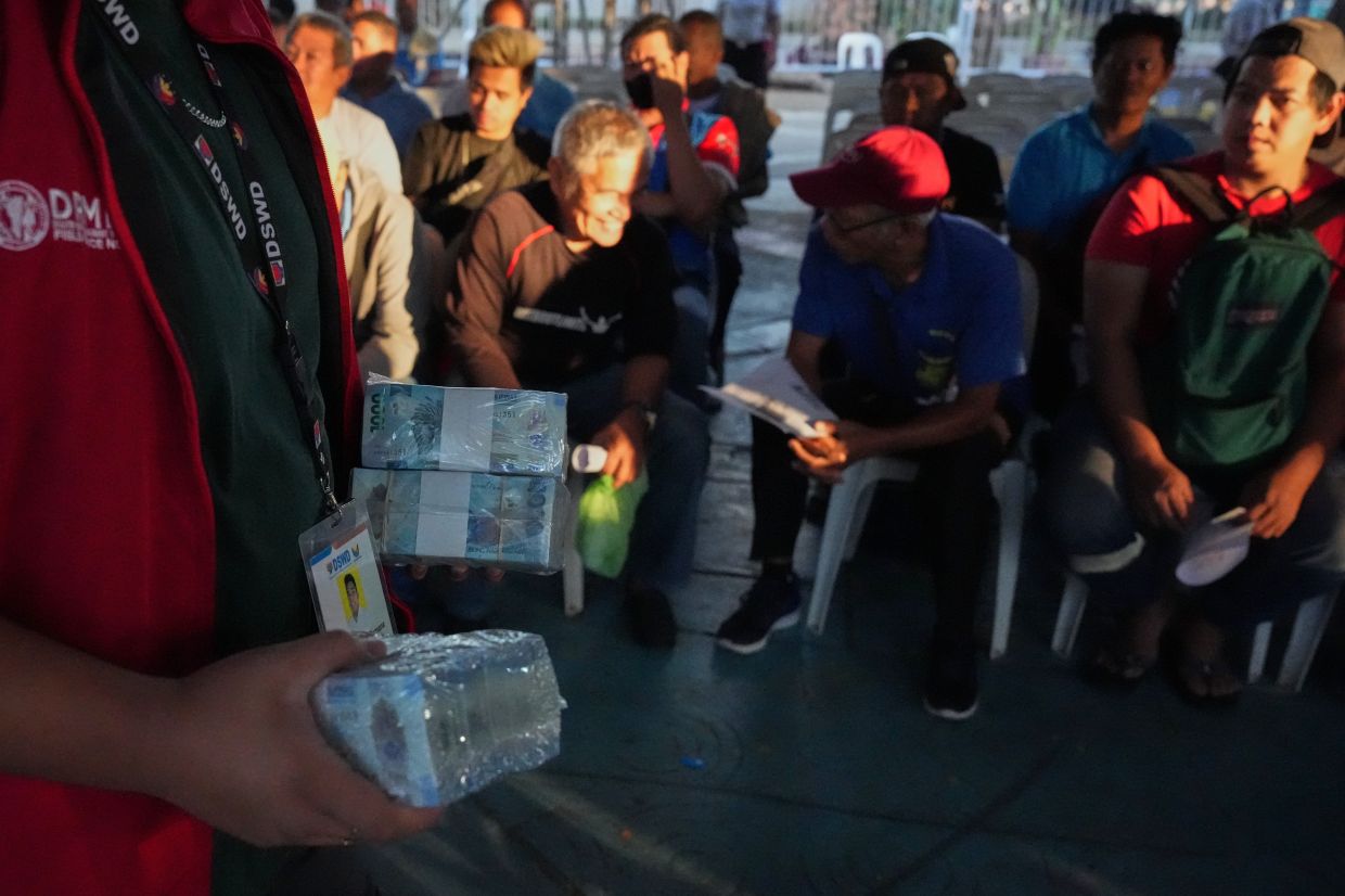 A worker carrying cash before a cash assistance programme for jeepney drivers from the government to help in their livelihood as oil prices continue to rise, on March 25, 2026, in Quezon city, Philippines. - AP 