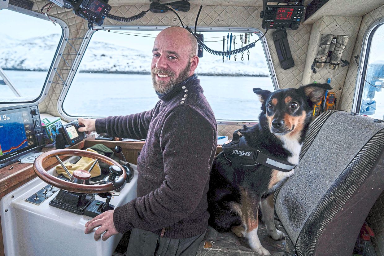 Aargil with his dog, Molly, sails on his boat near Nuuk.