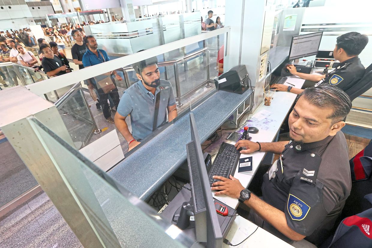 Mohd Khalifah (foreground) manning the Immigration checkpoint at Bangunan Sultan Iskandar Customs, Immigration and Quarantine complex on the first day of Hari Raya Aidilfitri as it is his turn to ‘hold the fort’. — Photos: THOMAS YONG/The Star