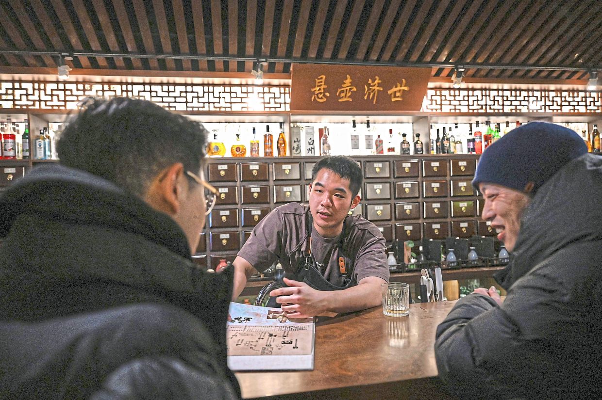 Customers being briefed on the selection of cocktails available. — AFP