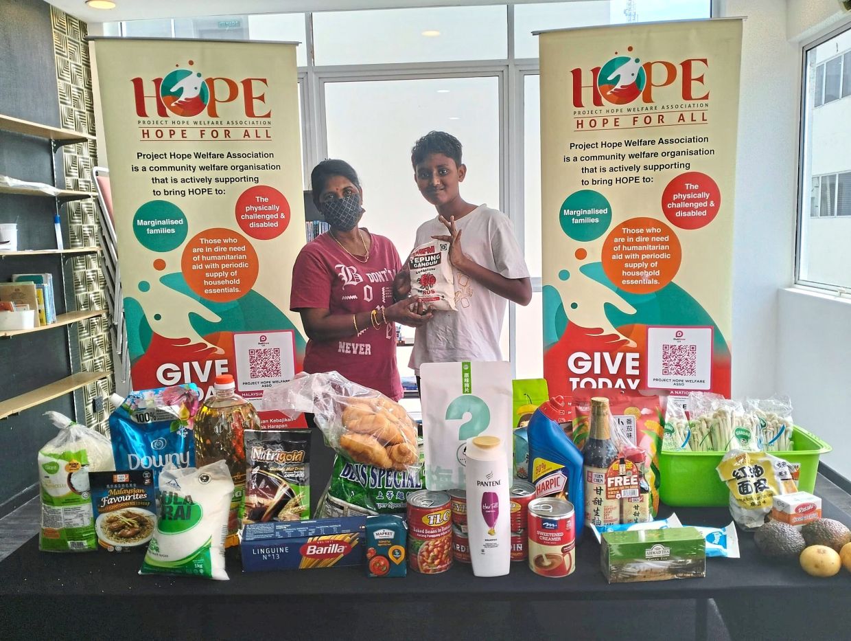 Zachary (right) often volunteers with his parents and sister to distribute foodstuff with Project Hope Welfare Association. Photo: Project Hope Welfare Association