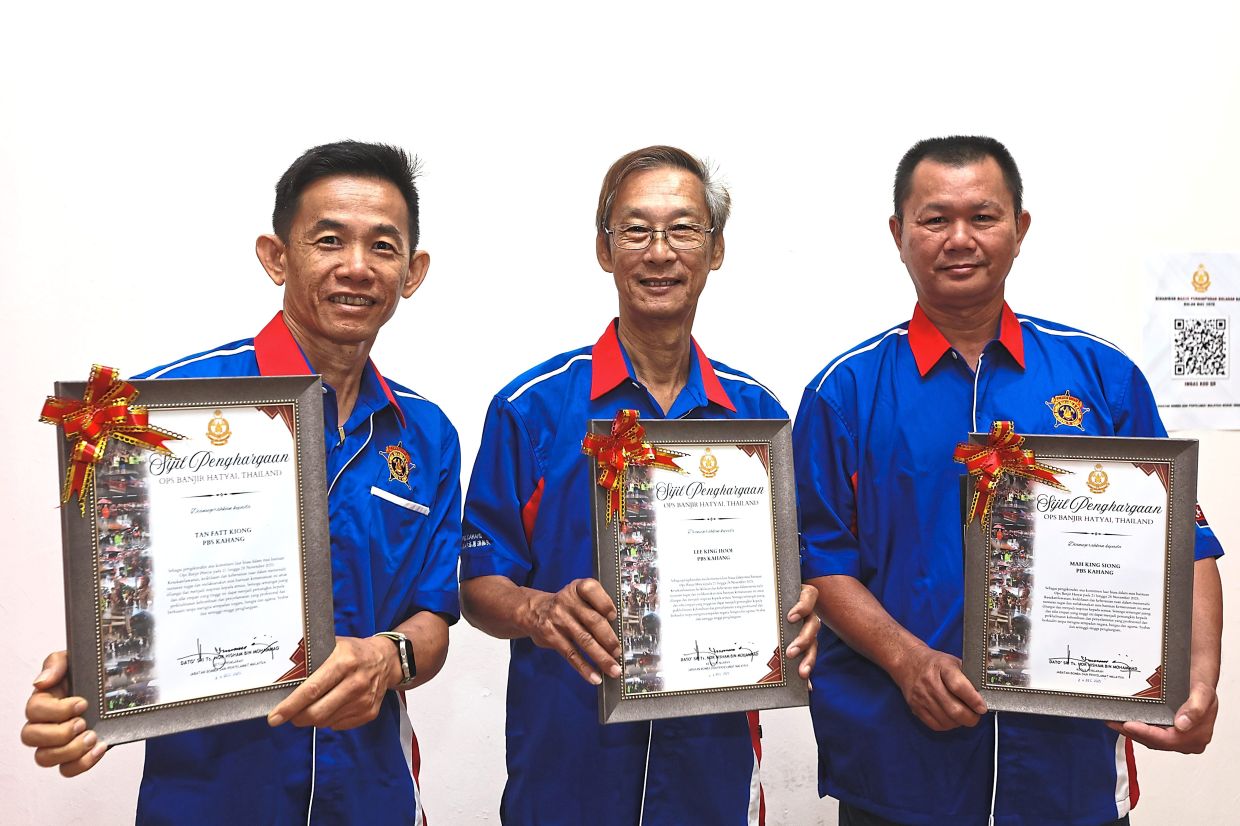 Lee (centre) with fellow volunteer firefighters from Kahang holding their certificates of appreciation for flood-assistance efforts in Hatyai. — Photos: THOMAS YONG/The Star