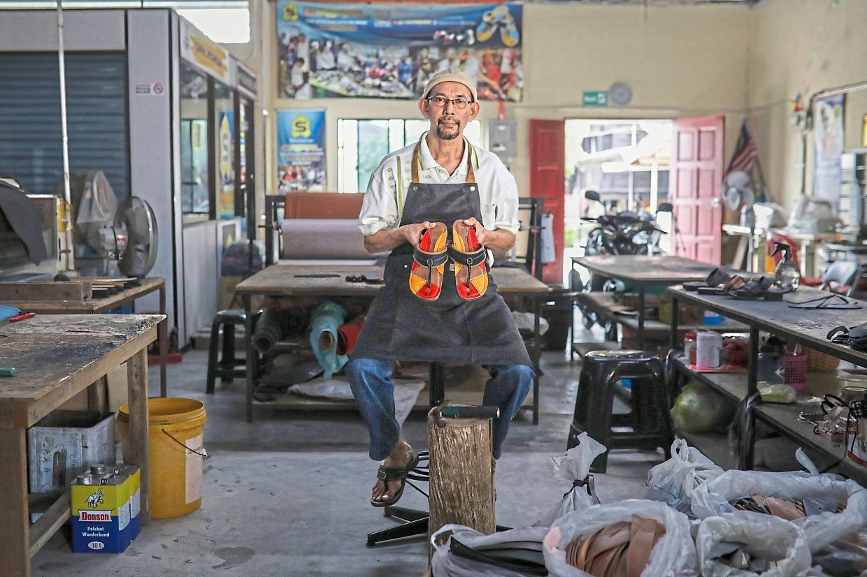 Saad, holding a pair of his handmade chappals, took the opportunity of being laid off to bring to life a Malay heritage artform. — Photos: Bernama