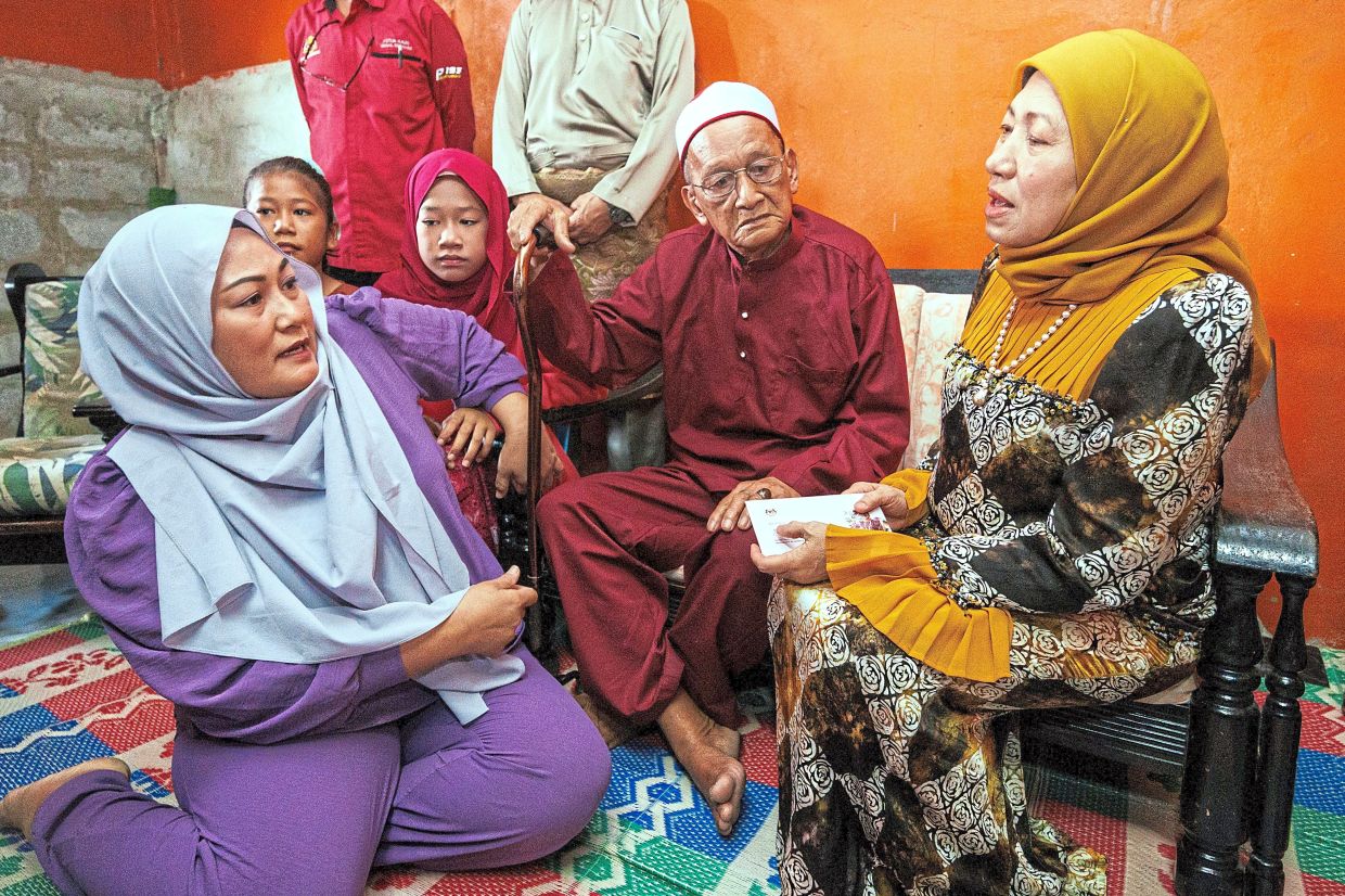 Raya outreach: Nancy handing over assistance to welfare recipient Norani Morni (left) during an Aidilfitri visit at Kg Tabuan Lot in Kuching. — ZULAZHAR SHEBLEE/The Star