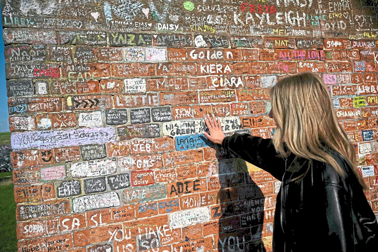 Former Harry Styles walking tour guide Thomason gestures to the names and messages written on the Twemlow Viaduct.