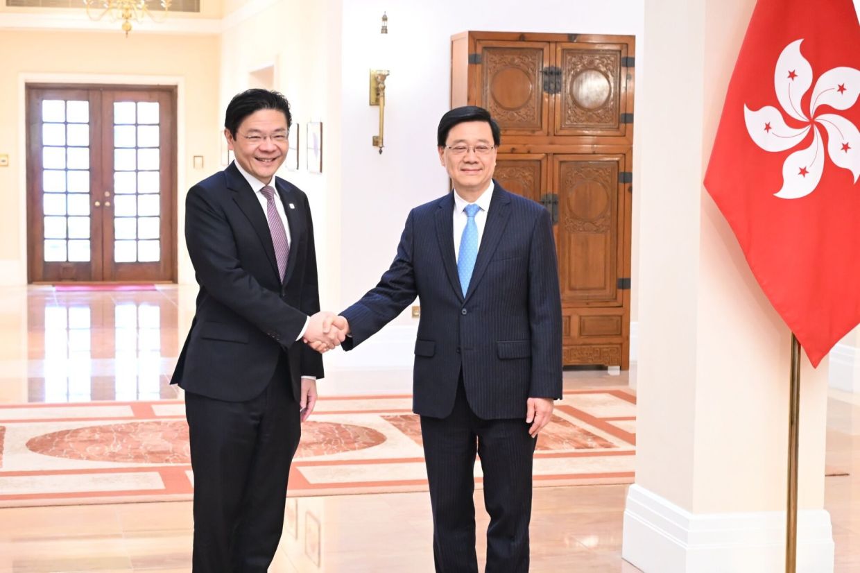 Lawrence Wong, Singapore's prime minister (left), shakes hands with John Lee, Hong Kong’s chief executive, at the Government House in Hong Kong, China, on Friday, March 27, 2026. Wong is on an official visit to Hainan and Hong Kong from March 25 to 28.-- Photographer: Peter Parks/AFP/Bloomberg