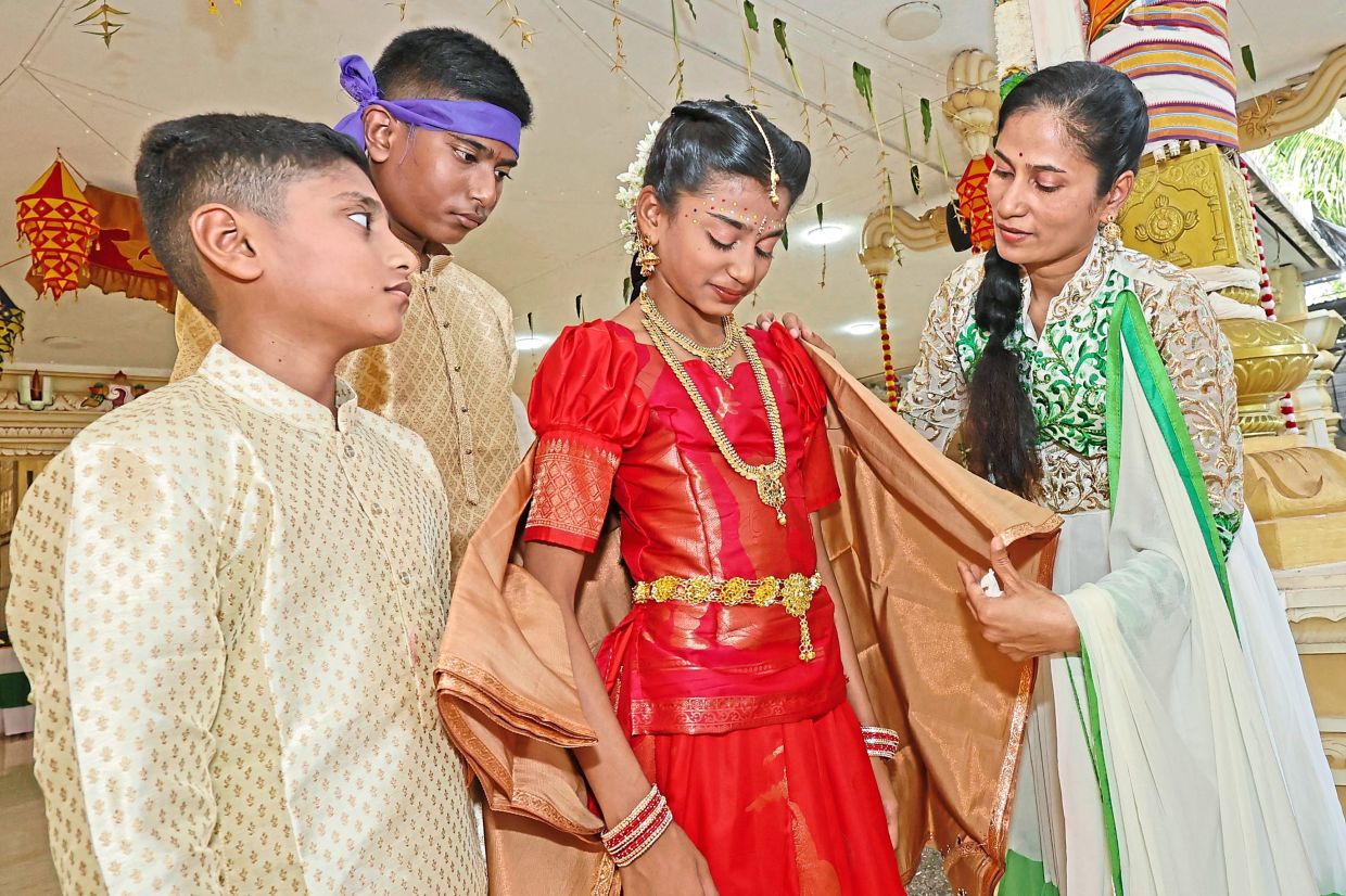 Suguna adjusting her daughter Divwany Chanthirasegar, 13, outfit as her sons look on at the Ugadi celebrations at Sri Ramar Temple, Solok York, George Town, Penang. —CHAN BOON KAI/The Star