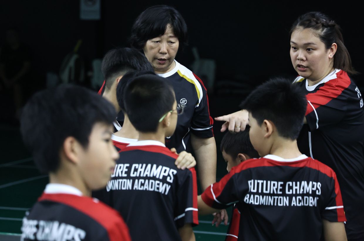 This is the way: Former player Lee Meng Yean having a word with her juniors at the Future Champs Badminton Academy, while head coach Zhang Hongyu looks on in Kepong. - AZMAN GHANI/The Star