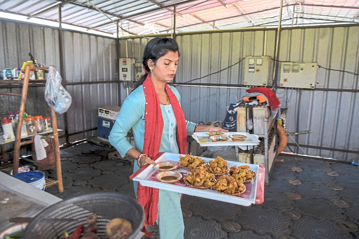 Savita carrying fries and snacks for customers at the floating restaurant.