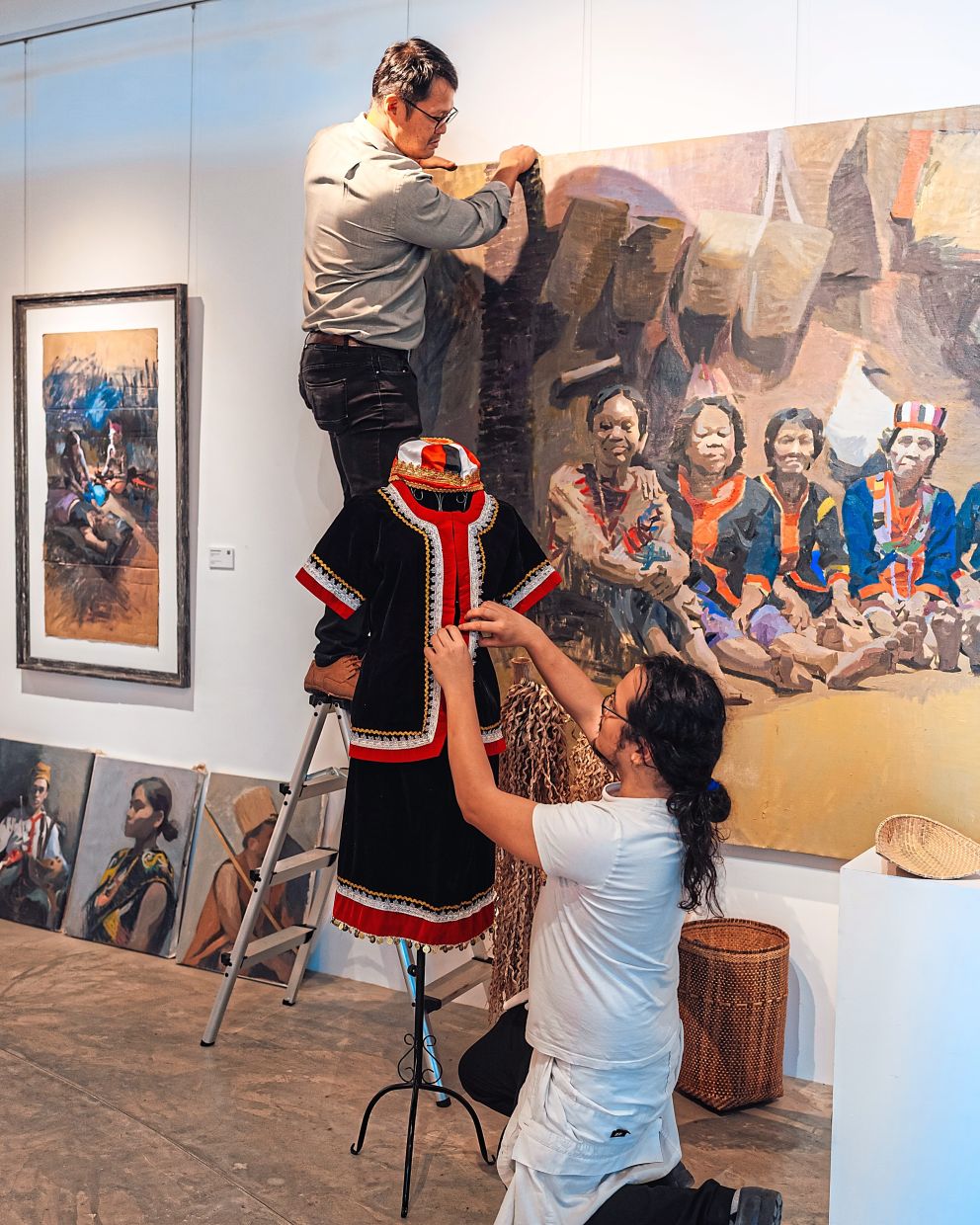 Hoan (left) and Ritom putting up the latter’s artwork for the exhibition.