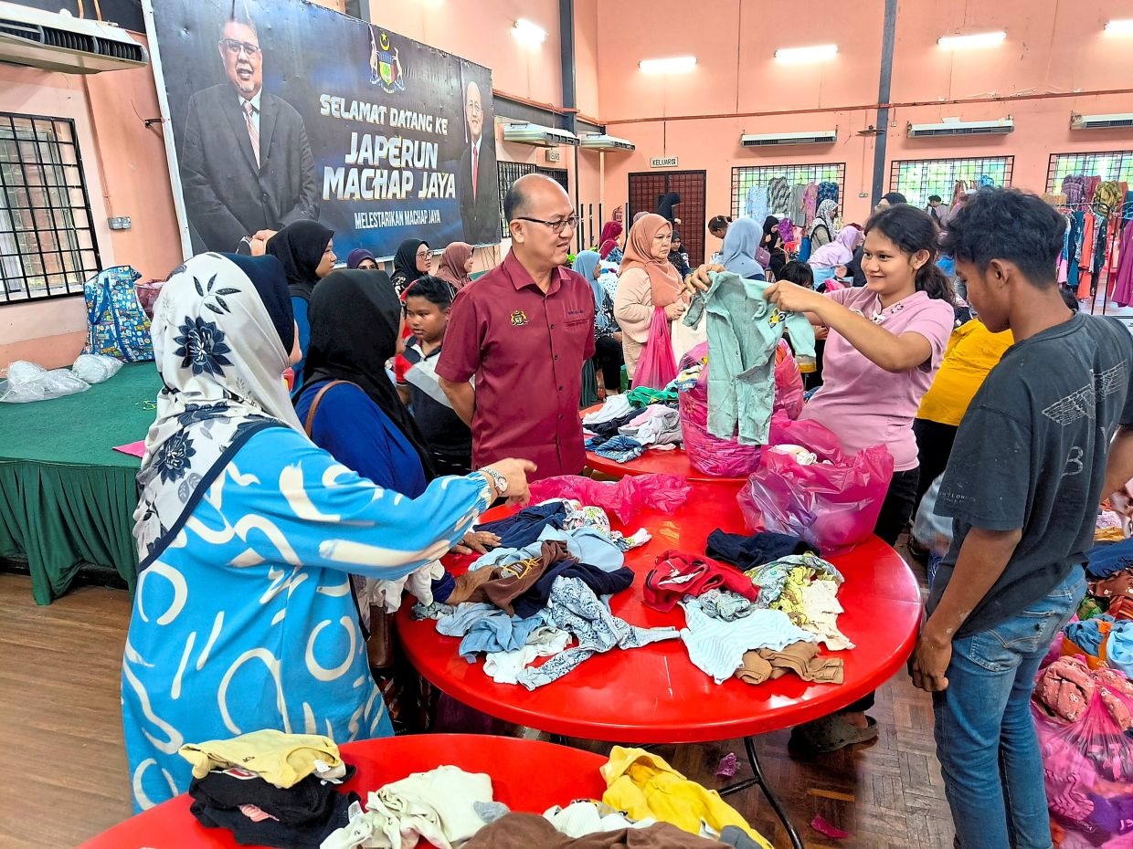 Visitors to the free market showing their finds to Ngwe. — Photos: Bernama 