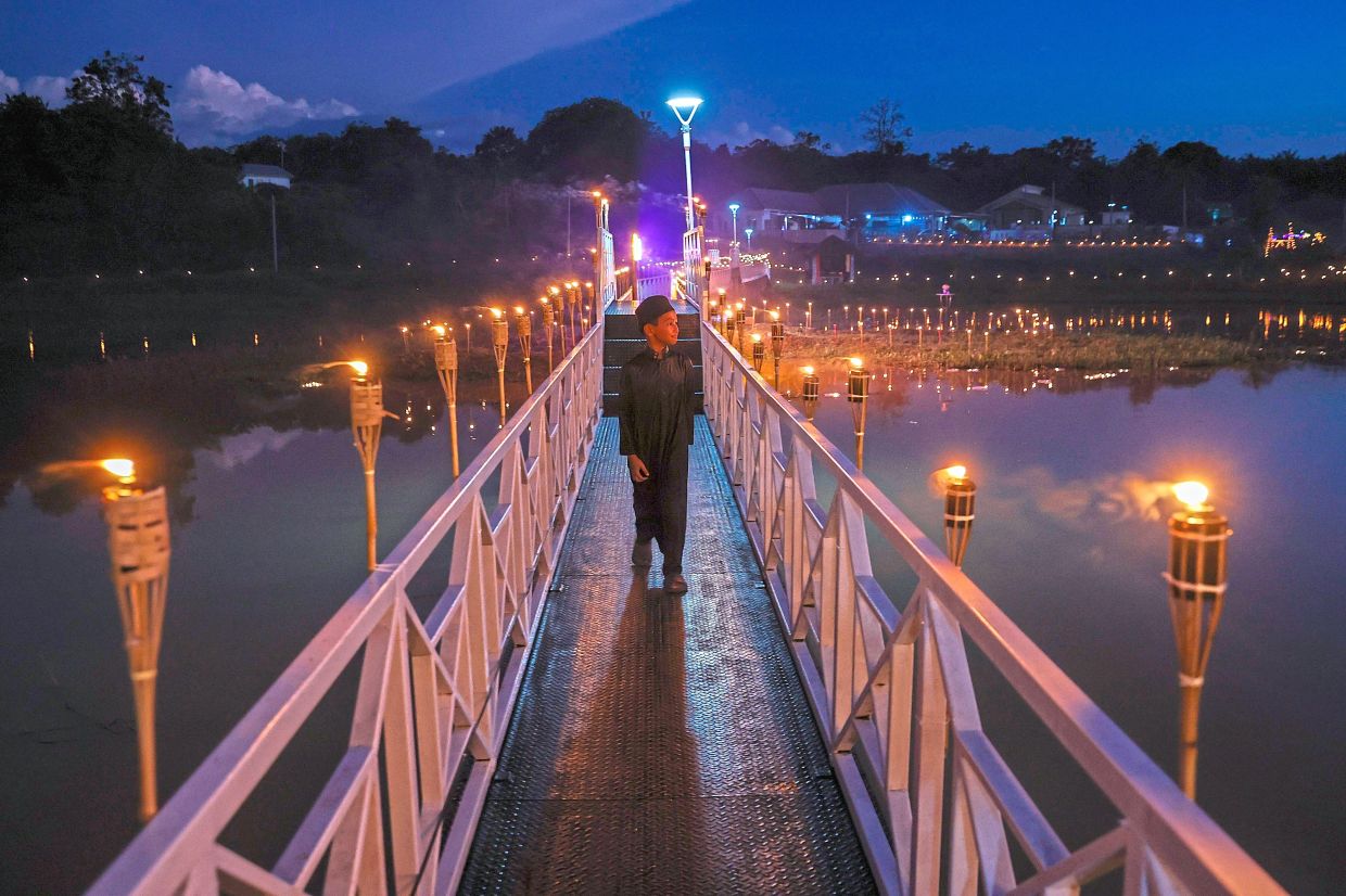 A boy walking along a pier lit by the glow of oil lamps.