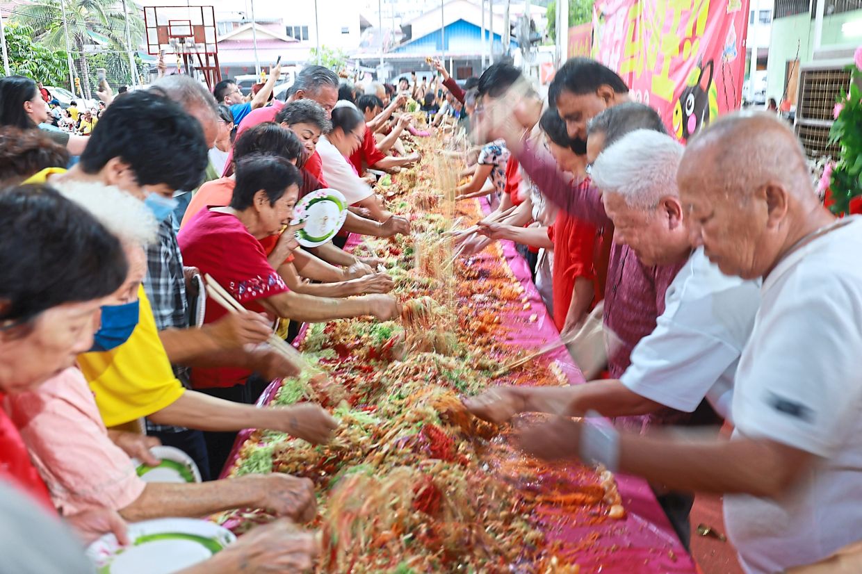 Residents participating in the yee sang tossing ceremony featuring a 15m-long loh sang setup.