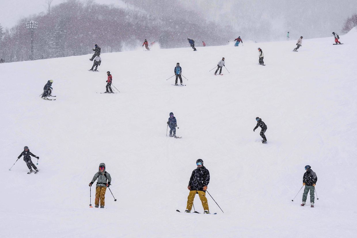 Tourists skiing and snowboarding in Niseko, where the snow is apparently powdery soft and perfect for these activities.