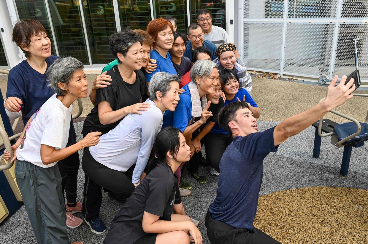 Coach Tan Shie Boon (right) is taking a group selfie with Singaporean elders after attending a parkour training session in Singapore. This is geriatric parkour, where around 20 retirees learned to tackle a series of relatively demanding exercises, building their agility and enjoying a sense of camaraderie. -- Photo by Roslan RAHMAN / AFP