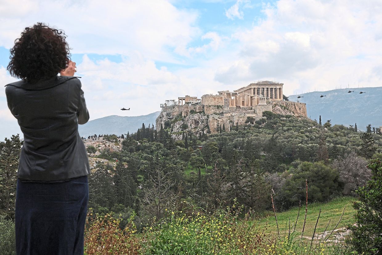 A woman taking pictures of the Acropolis of Athens in Greece.