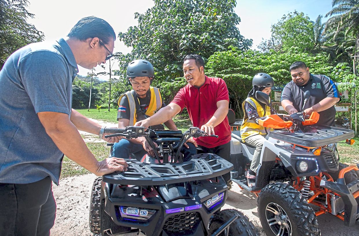 Che Wan (standing centre) showing visitors how to operate the ATV.