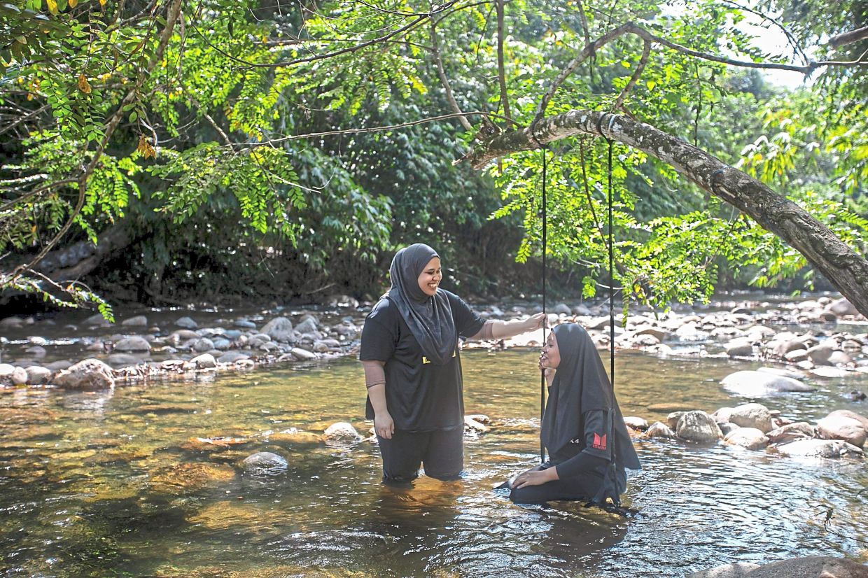 Amira Hanis (right) and Khairul Anisah appreciating nature and the cool river.