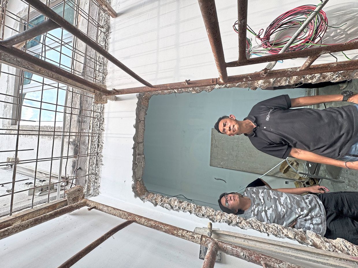  Loh (left) and another resident, Tan Ah Cheng, surveying repairs and rebuilding work being done on Tan’s house. 
