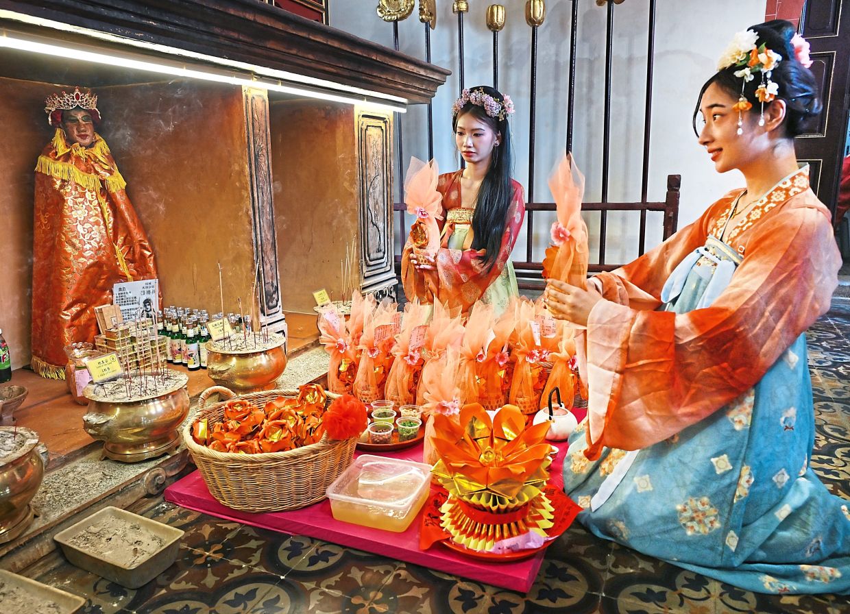 Mily Zhang, 24 (left) and Angell Teoh, 27, making offerings at Thai Pak Koong (Ng Suk) Temple in George Town. — Photos: KT GOH/The Star 
