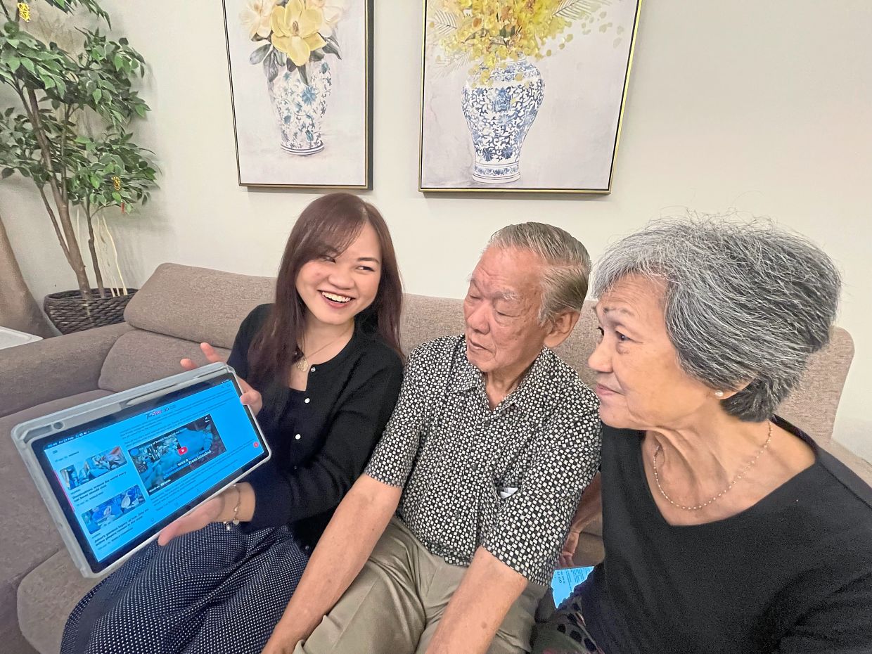 E-Lyse (left) guides her grandparents on how to read news online.