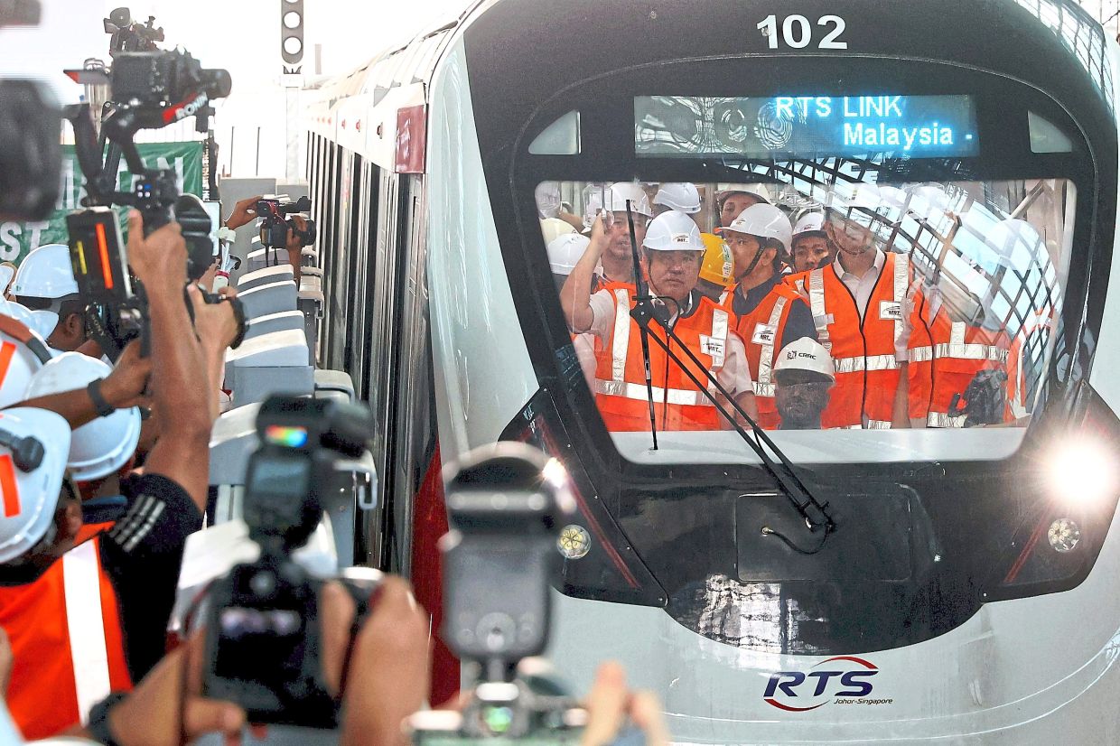 Rail check: Loke (left) riding the RTS Link coach during his site visit. — THOMAS YONG/The Star