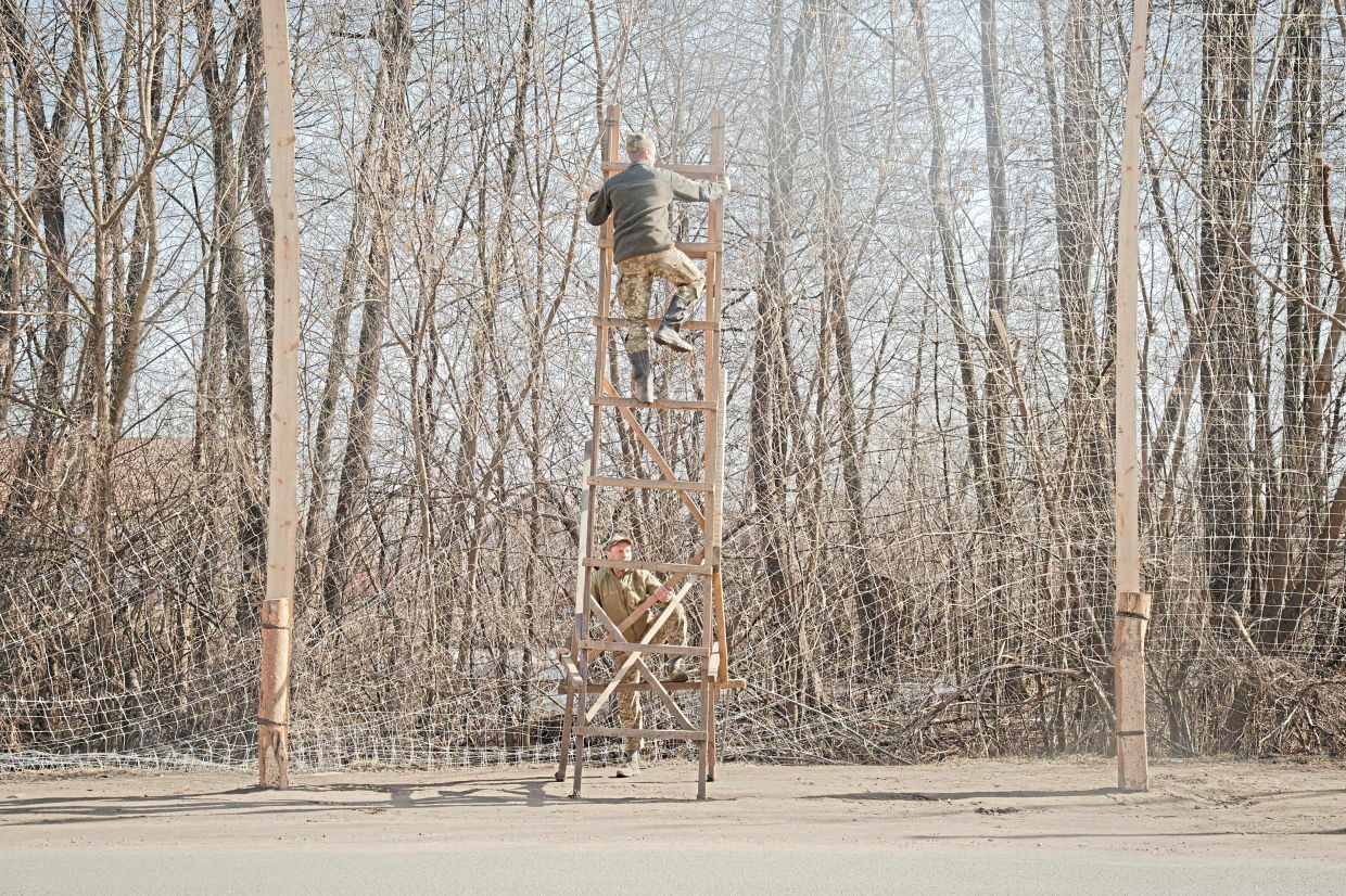 Ukrainian soldiers installing anti-drone netting at the entrance to the city of Izium, Kharkiv region, amid the Russian invasion of Ukraine. — AFP