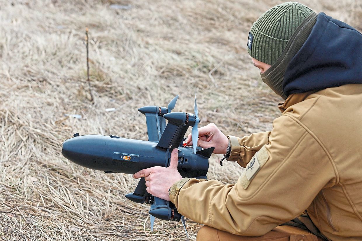 (Right) A technician checking an FPV interceptor drone before flying it at a training ground during an examination for military drone operators at an undisclosed location in Ukraine. -Reuters