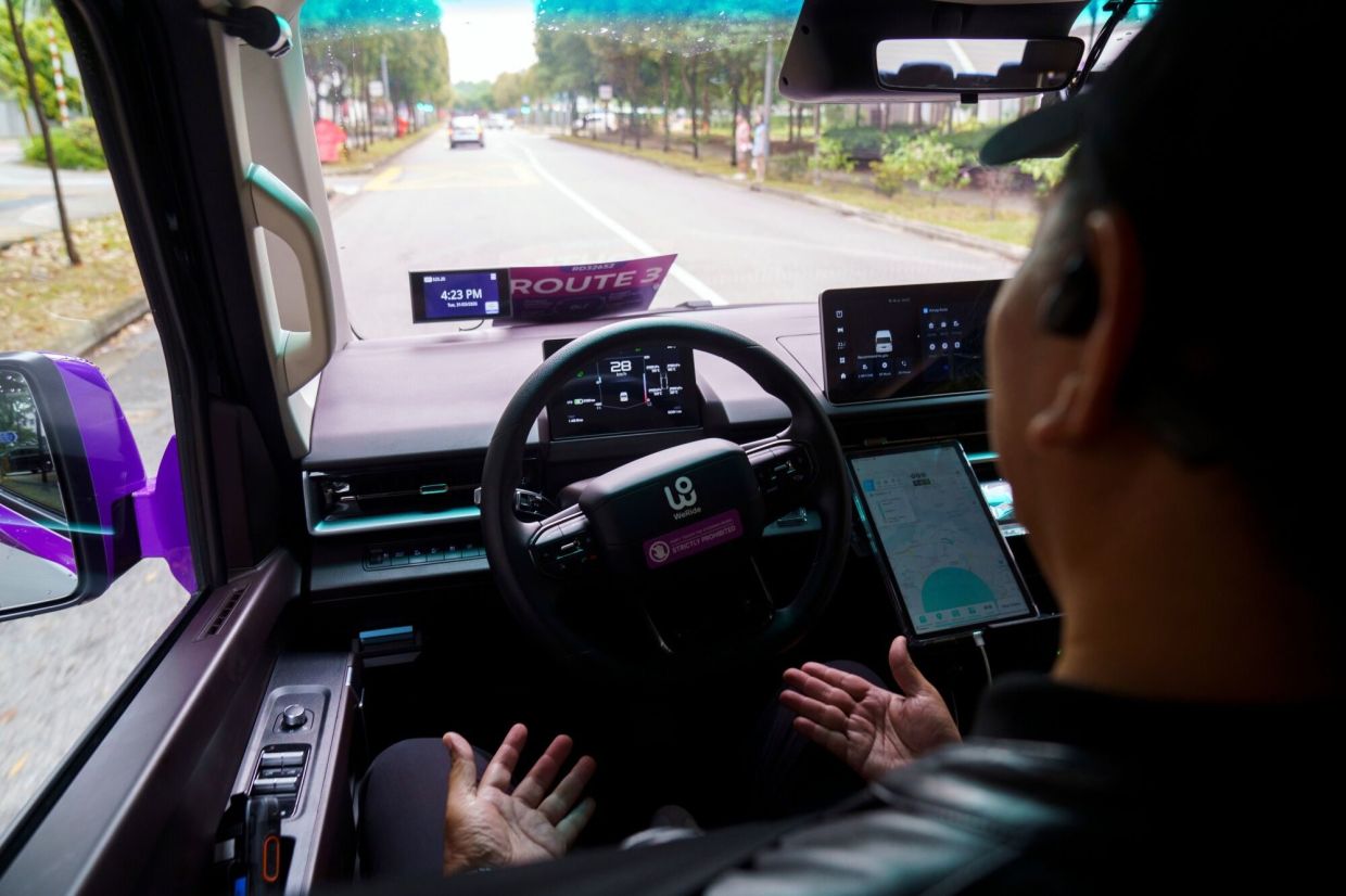 A safety officer is in the driver's seat onboard a GRX robotaxi, operated by Grab Holdings Ltd. and WeRide Inc., in Singapore. Singapore's Grab became Southeast Asia's first ride-hailing provider to launch a driverless service, betting that the technology can help cut costs and prove out robotaxis in dense urban traffic. -- Photographer: Ore Huiying/Bloomberg